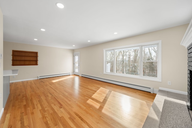 unfurnished living room featuring light wood-type flooring, a wealth of natural light, and baseboard heating