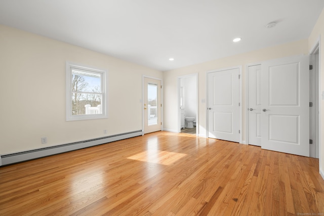 interior space with a baseboard heating unit, access to exterior, and light wood-type flooring