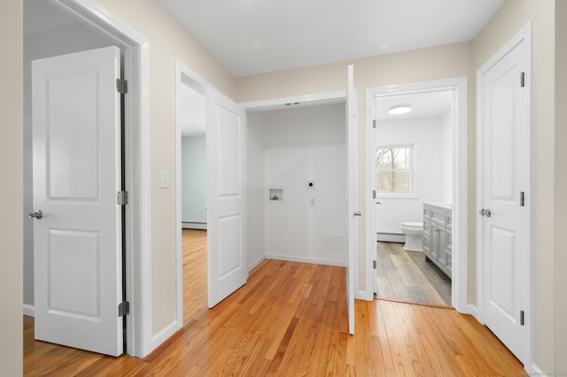 corridor with a baseboard heating unit and light hardwood / wood-style floors