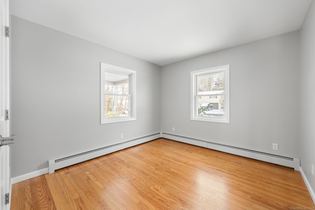 unfurnished room with baseboard heating and light hardwood / wood-style flooring