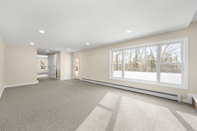 empty room featuring a wealth of natural light, light colored carpet, and baseboard heating