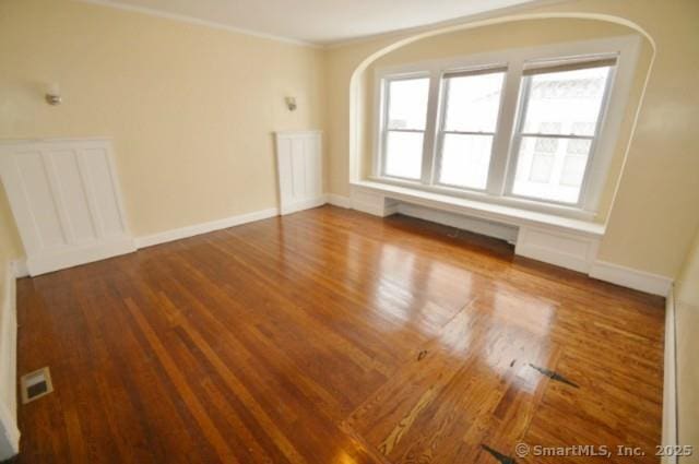 empty room with ornamental molding and hardwood / wood-style floors