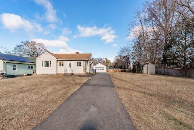 view of front facade featuring a storage shed, a garage, and a front yard