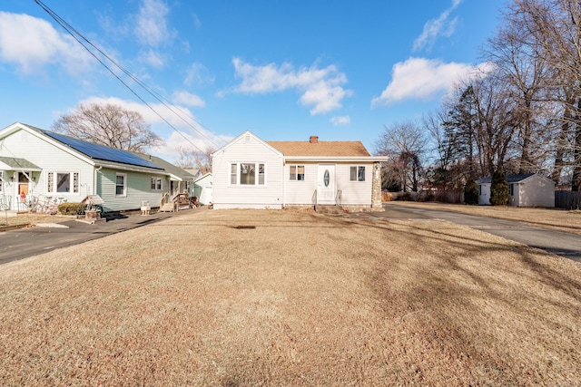 view of front of home with a storage shed and solar panels