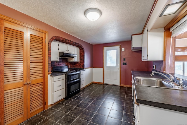 kitchen with white cabinetry, sink, dark tile patterned flooring, range with two ovens, and a textured ceiling