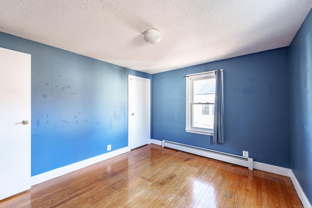 empty room featuring hardwood / wood-style floors, a baseboard radiator, and a textured ceiling