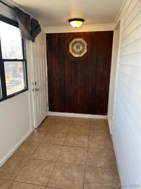 doorway to outside featuring wooden walls and light tile patterned flooring