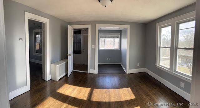 unfurnished room with dark wood-type flooring and radiator