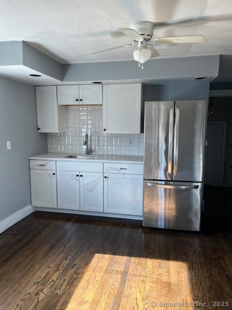 kitchen featuring dark hardwood / wood-style floors, stainless steel refrigerator, sink, white cabinets, and decorative backsplash