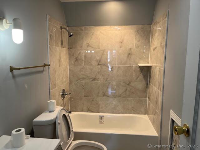 full bathroom featuring tiled shower / bath, vanity, and toilet