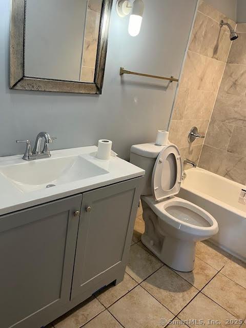 full bathroom with vanity, tile patterned flooring, tiled shower / bath combo, and toilet