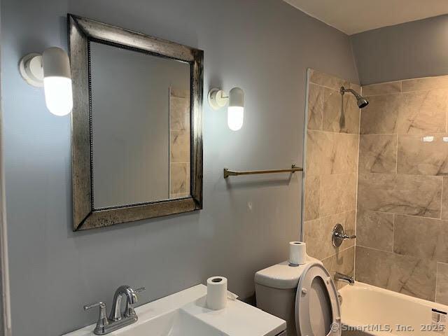 full bathroom with tiled shower / bath combo, vanity, and toilet