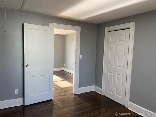 unfurnished bedroom with a closet and dark hardwood / wood-style floors