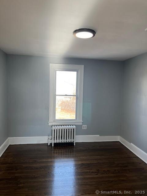 empty room with radiator heating unit and dark hardwood / wood-style floors