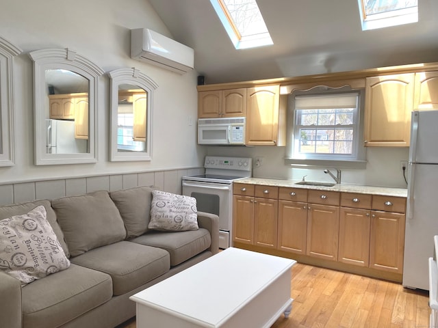 kitchen featuring white appliances, vaulted ceiling with skylight, open floor plan, an AC wall unit, and a sink