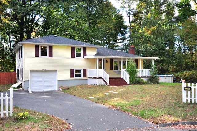 split level home with a garage, a front yard, and covered porch