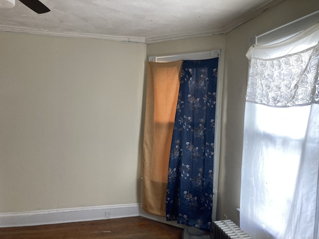 unfurnished room with dark wood-style floors, ceiling fan, ornamental molding, and baseboards