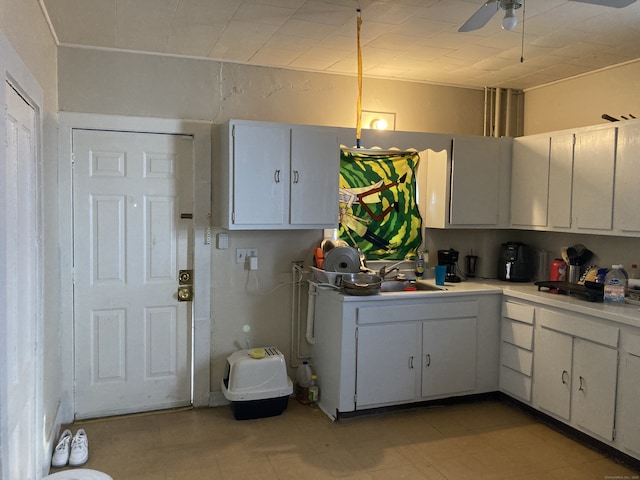 kitchen featuring ceiling fan, white cabinetry, light countertops, and a sink