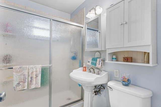 bathroom featuring toilet and a shower with shower door