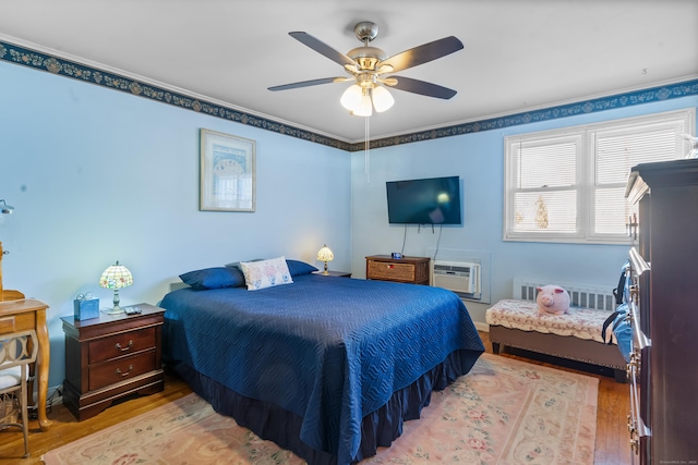 bedroom with ceiling fan, a wall mounted AC, and light wood-type flooring