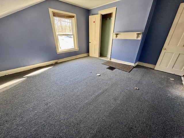 unfurnished bedroom with lofted ceiling and dark carpet