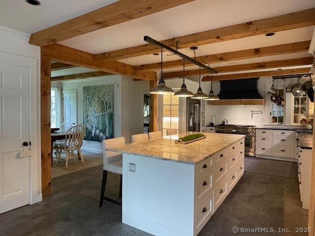 44 Brook St, Groton, CT 06340 - kitchen with white cabinetry, a kitchen island, beam ceiling, extractor fan, and high end stainless steel range oven