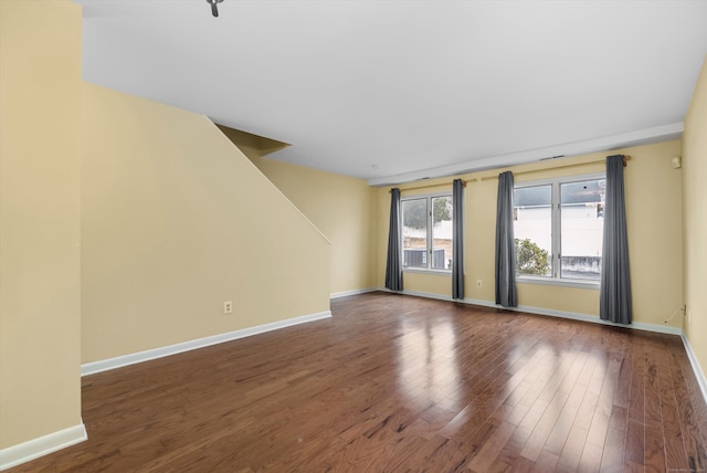 spare room with baseboards and wood finished floors