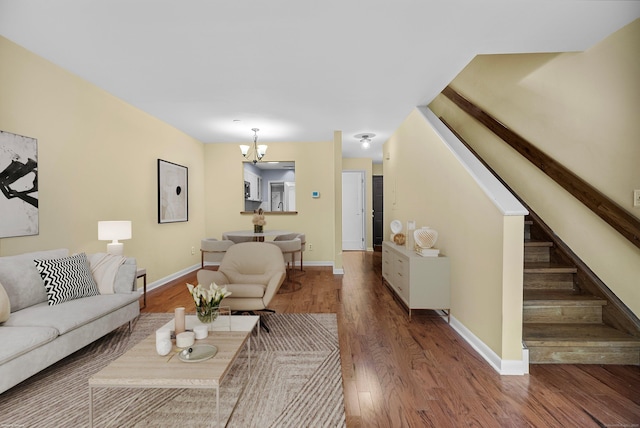 living area featuring baseboards, a notable chandelier, stairway, and wood finished floors