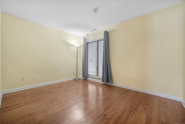 empty room with baseboards, visible vents, and wood finished floors