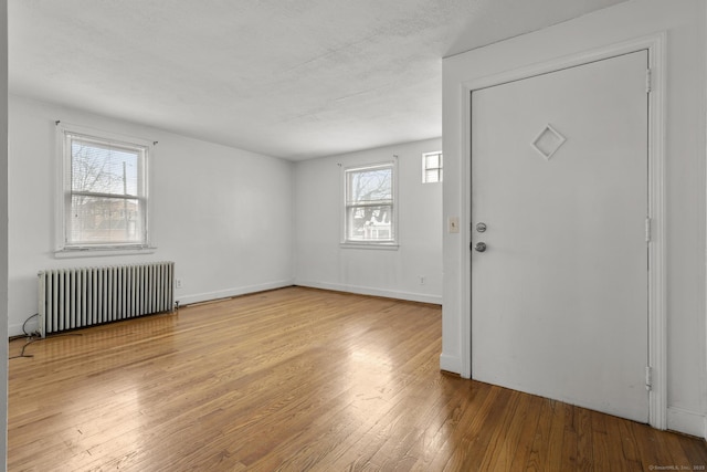 foyer entrance with radiator heating unit and light wood-type flooring