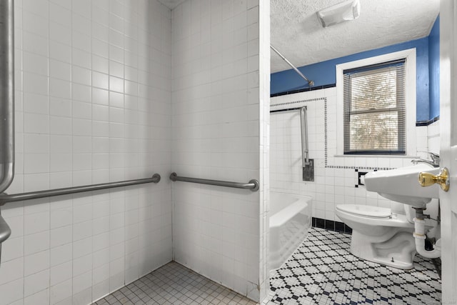 bathroom with tiled shower / bath, tile walls, tile patterned flooring, toilet, and a textured ceiling