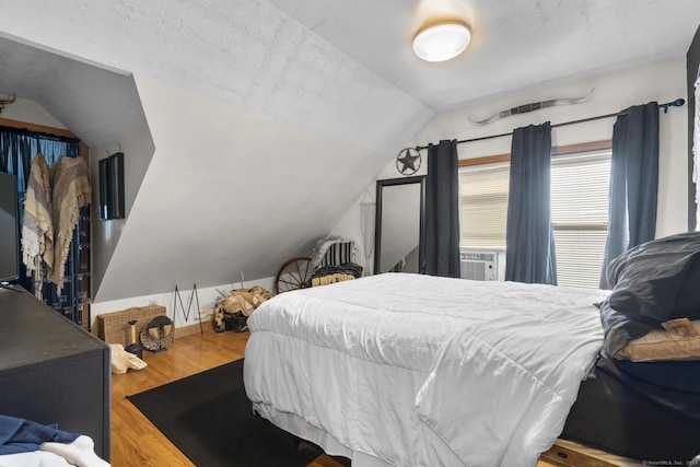 bedroom with hardwood / wood-style flooring, vaulted ceiling, and cooling unit