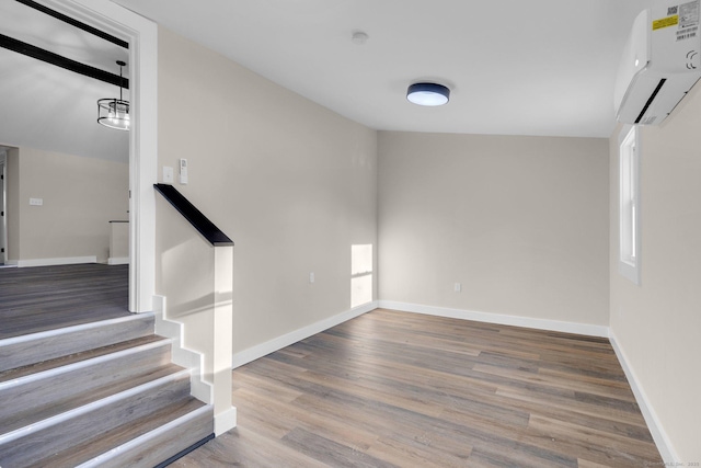 stairs with lofted ceiling, wood-type flooring, and a wall mounted AC