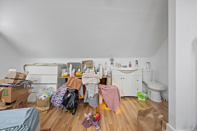 interior space featuring vaulted ceiling, toilet, and hardwood / wood-style floors