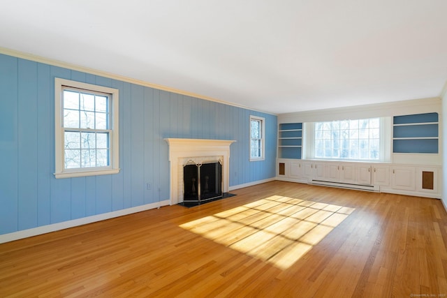 unfurnished living room with a brick fireplace, a baseboard heating unit, a wealth of natural light, and light hardwood / wood-style flooring