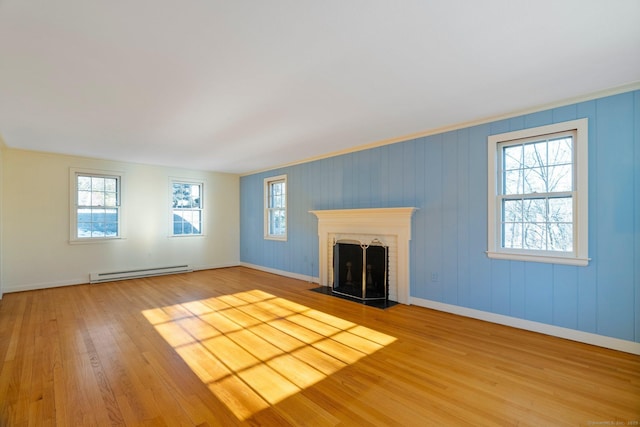 unfurnished living room with hardwood / wood-style flooring, a baseboard radiator, and plenty of natural light