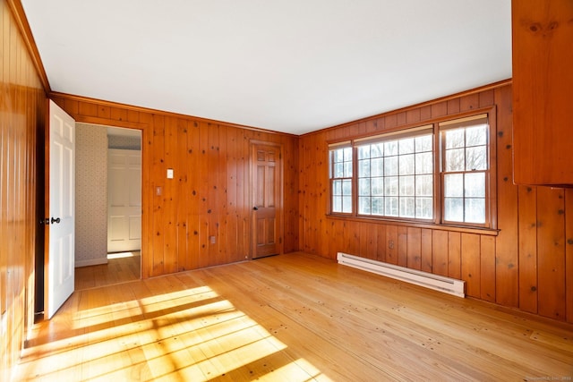 spare room featuring a baseboard heating unit and light wood-type flooring