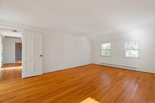 empty room featuring baseboard heating, lofted ceiling, and light hardwood / wood-style flooring