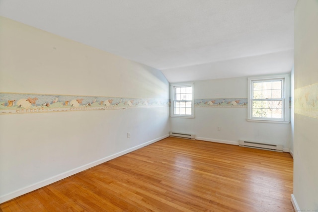 unfurnished room with lofted ceiling, light hardwood / wood-style floors, and a baseboard heating unit