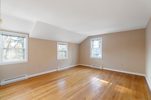 additional living space featuring baseboard heating, vaulted ceiling, and light hardwood / wood-style flooring