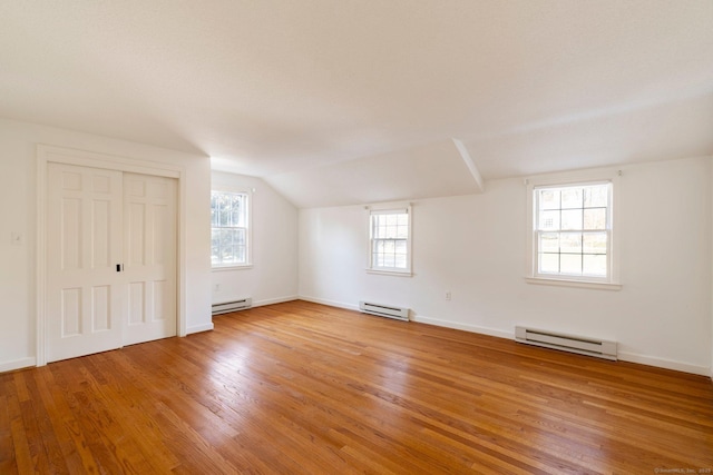 additional living space featuring a baseboard radiator, wood-type flooring, and vaulted ceiling