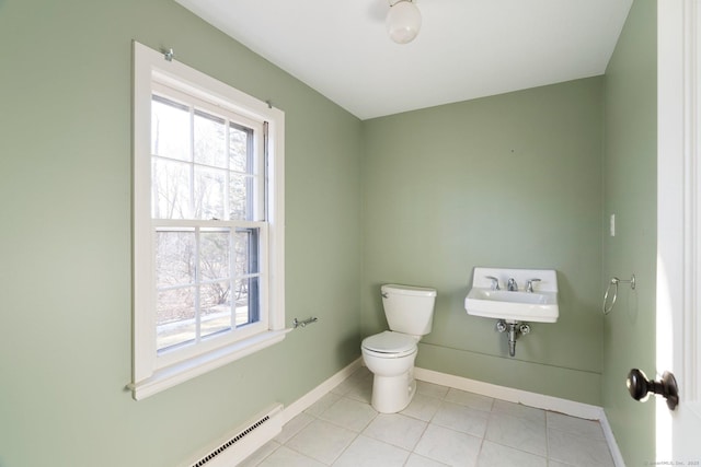 bathroom with a wealth of natural light, tile patterned floors, baseboard heating, and toilet