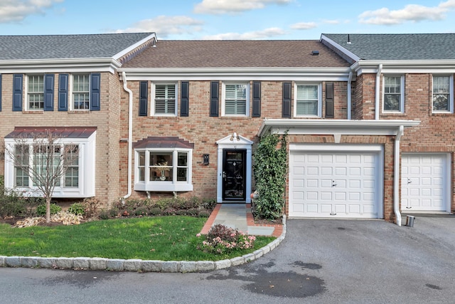 townhome / multi-family property featuring a garage and a front lawn