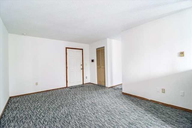 spare room featuring a textured ceiling and dark colored carpet