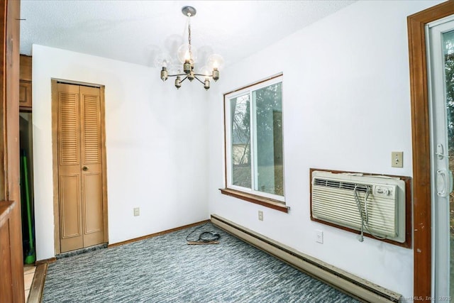 spare room featuring an AC wall unit, carpet flooring, a baseboard heating unit, a notable chandelier, and a textured ceiling