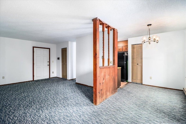 carpeted spare room with a textured ceiling and a notable chandelier