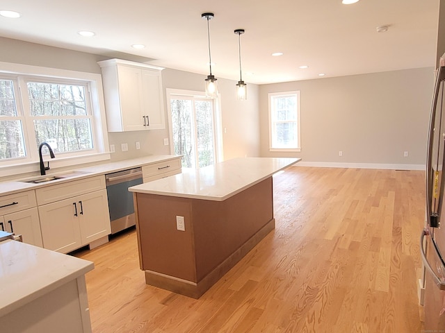 kitchen with decorative light fixtures, white cabinetry, sink, a center island, and stainless steel dishwasher