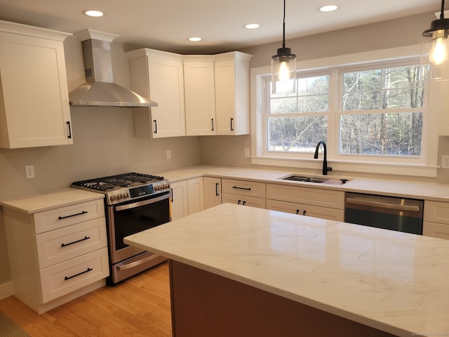 kitchen featuring pendant lighting, sink, stainless steel appliances, light stone counters, and wall chimney exhaust hood