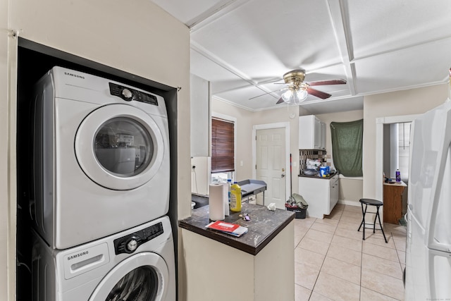 clothes washing area featuring stacked washer / dryer, light tile patterned flooring, and ceiling fan