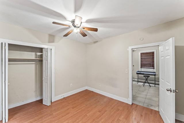 unfurnished bedroom featuring a baseboard radiator, a closet, ceiling fan, and light hardwood / wood-style flooring